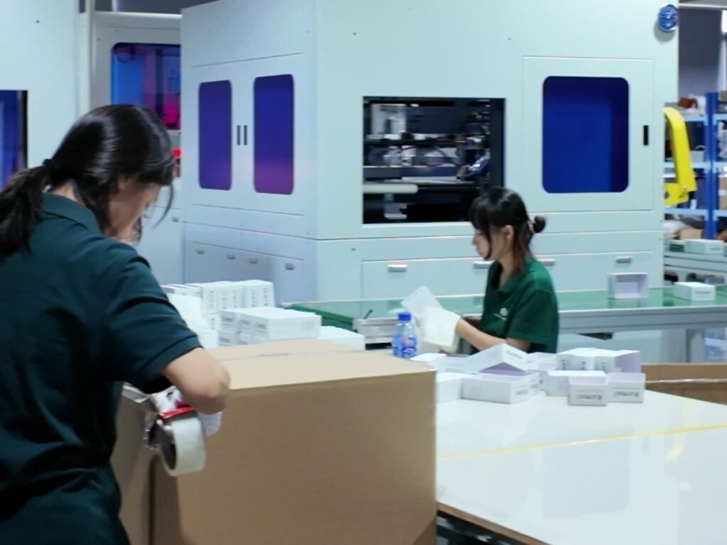 Worker packing finished boxes into a corrugated shipping carton